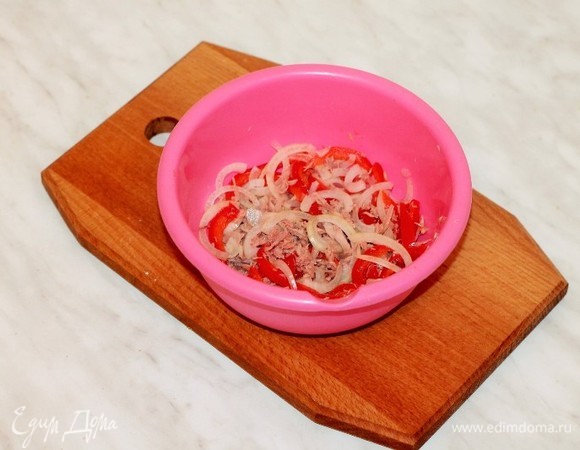 Нарезать лук тонкими полукольцами и залить горячей водой. Добавить лимонный сок и щепотку сахара. Остывшую воду слить, лук выложить в миску. Добавить болгарский перец, нарезанный тонкими полосками.