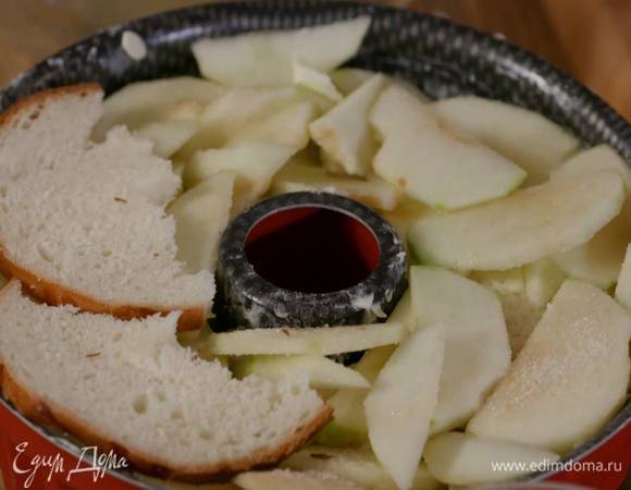 Форму для выпечки с выемкой посередине слегка смазать сливочным маслом, уложить слой яблок, немного посыпать их сахаром, выложить слой бриоши, а сверху несколько небольших кусочков сливочного масла комнатной температуры. Повторять выкладывать слои таким образом, пока форма не заполнится (последний слой должен получиться из сдобы, маслом его смазывать не нужно), и плотно все прижать.