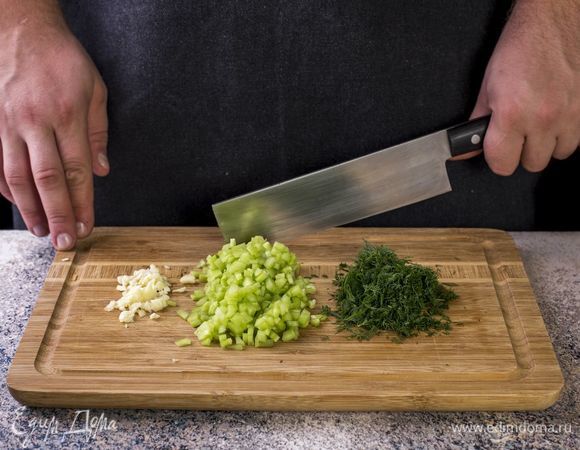 Подготовьте соус. Огурец помойте, снимите с него кожуру и мелко нарежьте. Чеснок и укроп мелко порубите.