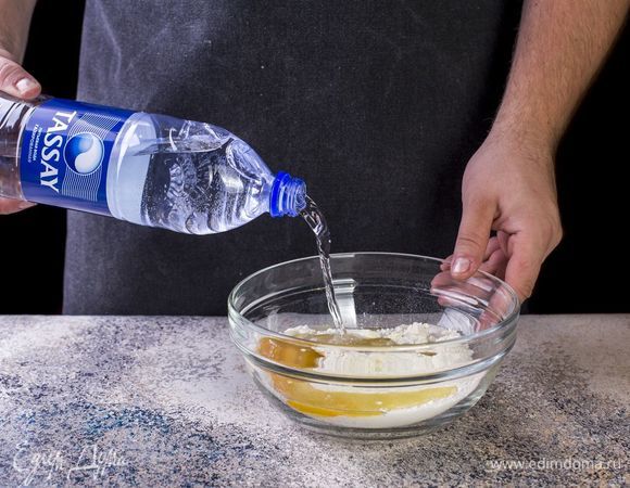 Добавьте к тесту газированную воду Tassay. Замесите упругое и эластичное тесто. Накройте тесто пищевой пленкой и оставьте на 20 минут.