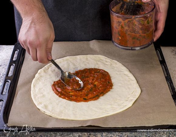 Раскатайте тонкое тесто. Смажьте его поверхность томатным соусом.