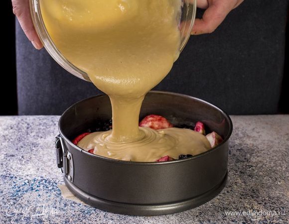 Форму для выпекания смажьте растительным маслом, застелите пергаментом. Яблоки перемешайте с черной смородиной. Выложите на дно формы. Залейте тестом.