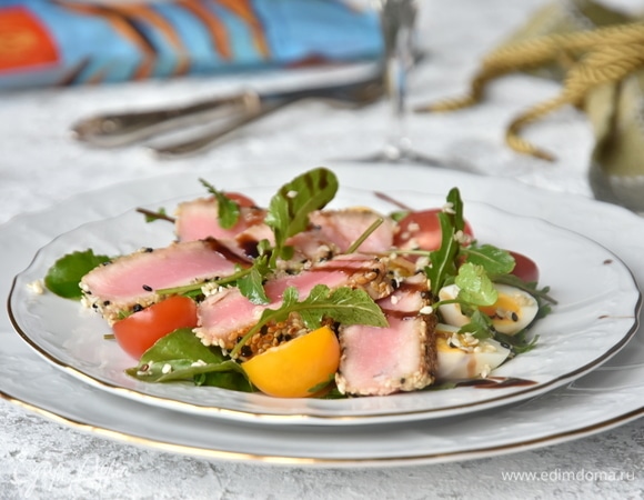 На подготовленную тарелку выложить подушку из листьев руколы. Разложить половинки перепелиных яиц и помидоров черри. Добавить ломтики филе тунца и сбрызнуть небольшим количеством бальзамического крема или соуса. Подавать блюдо сразу после сервировки.