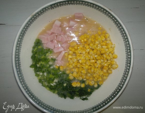 В омлетную массу добавить зелень, зеленый лук, ветчину, вареную кукурузу, перемешать.
