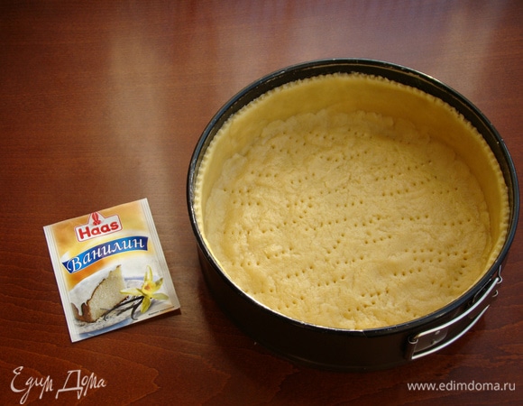 Дно формы для выпечки (20–22 см) застелить пекарской бумагой и равномерным слоем выложить песочное тесто, делая высокие бортики. Дно наколоть вилкой и поставить в холодильник минут на 30.