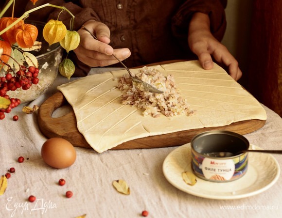 Делаем продольные надрезы, начиная от того места, где будет заканчиваться начинка. Выкладываем в центр начинку. Для сочности можно добавить сливочное масло. Затем каждую полоску попеременно укладываем на пирог по типу косички.