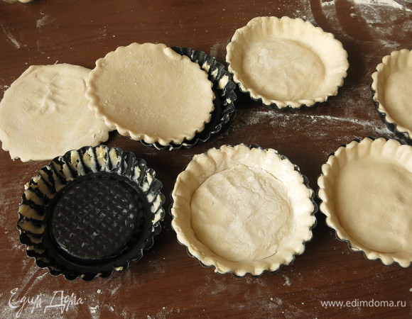 На 6 тарталеток вырезаем круги из теста и выкладываем в смазанные формы. Протыкаем вилкой.