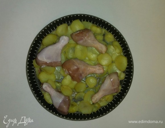 Через 25 минут достаем противень с картошкой и выкладываем на нее куриные голени.