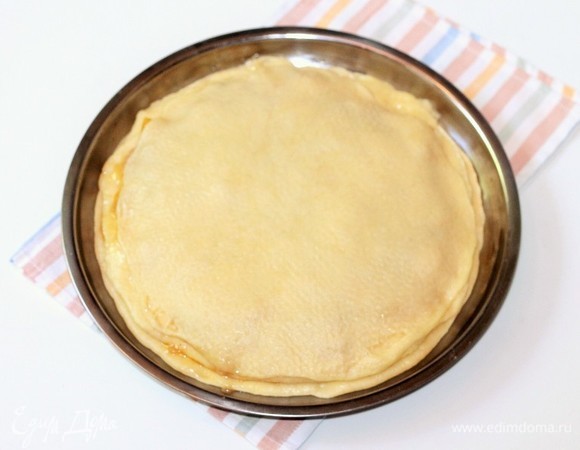 Одну часть теста раскатываем в круг и закрываем начинку. Край круга смазываем взбитым желтком.