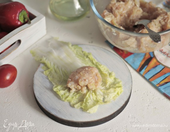 Острым ножом срезаем толстое основание у листьев салата. На край выкладываем фарш и заворачиваем по типу конвертика.
