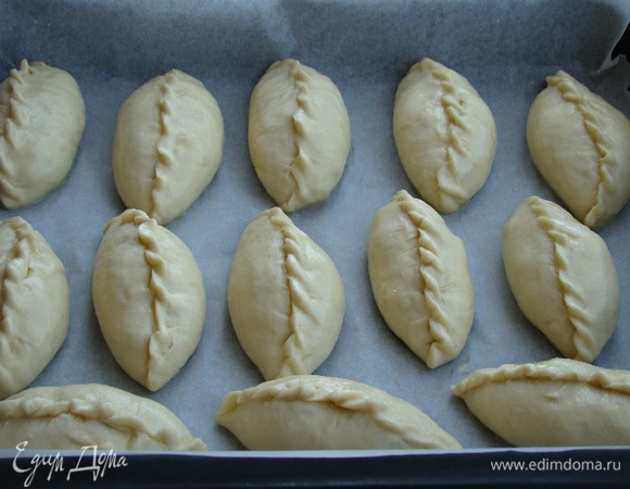 Готовые пирожки оставить минут на 30 для расстойки. За это время разогреть духовку до 190°C. Пирожки смазать взбитым яйцом и поставить в разогретую духовку примерно на 30 минут, пока те не подрумянятся.