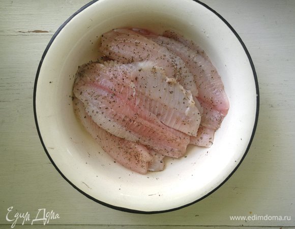 С тилапии слить воду, промыть, обсушить. Сбрызнуть рыбу лимонным соком, посыпать сушеным базиликом и перцем. Дать постоять 15 мин.