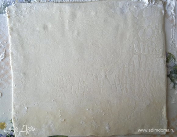 Слоеное бездрожжевое тесто заранее разморозить при комнатной температуре (время размораживания учтено в подготовке). На подпыленном мукой столе раскатать пласты в форме прямоугольников. У меня получилось 3 пласта размером 22х25 см.