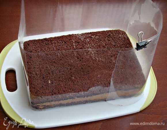 Бисквит разрезать на два коржа, промазать остывшим заварным шоколадным кремом Haas. Так как у меня форма для выпечки не разъемная, я сделала импровизированные бортики из ацетатной пленки. Торт поставить в холодильник примерно на полчаса, чтобы схватился крем.