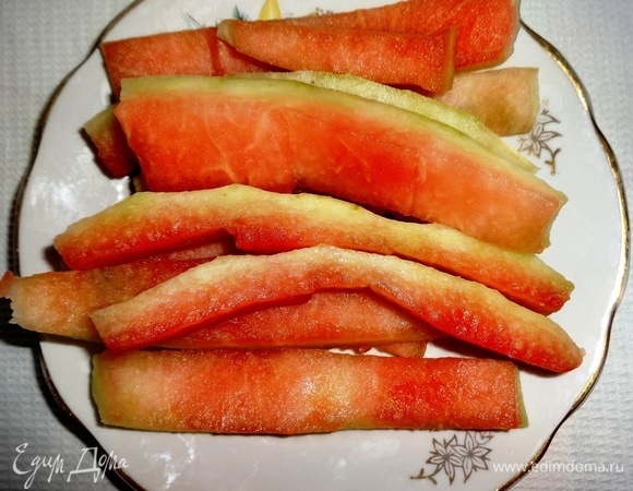 После того как съели арбуз, собрать арбузные корочки и промыть под проточной водой. Положить в дуршлаг, чтобы полностью стекла вода. Затем обсушить бумажным полотенцем. Острым ножом аккуратно срезать тонким слоем зеленую часть корочки и подровнять краешек с другой стороны. Розовую часть немного оставить, до конца не срезать. От одного арбуза получается не очень много арбузных корочек. Я делаю так: подготавливаю корочки, нарезаю и порциями замораживаю. Затем достаю из морозилки, размораживаю и засыпаю сахаром. Количество ингредиентов указала примерное, ориентируйтесь на свой вкус. У меня большой таз объемом 4,5 литра, который я полностью заполняю корочками и засыпаю сахаром. В конце варки получается примерно половина таза варенья, т.е. выходит примерно 2 с небольшим литра.