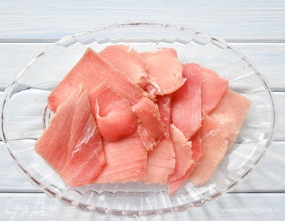Филе тунца, не размораживая до конца, нарезать тонкими слайсами, разложить на блюде.