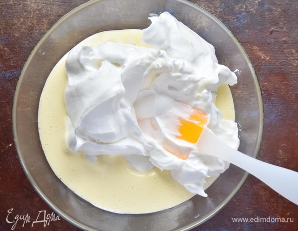 Отдельно взбить белки до устойчивой плотной пены, постепенно добавляя оставшийся сахар. Соединить белки с желтками и аккуратно перемешать получившуюся массу.
