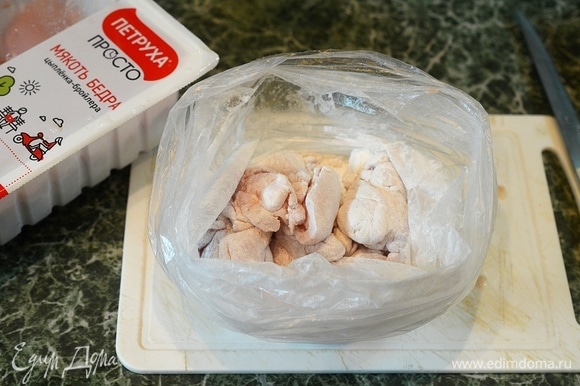 Добавьте кусочки курицы и хорошо потрясите пакет, чтобы каждый кусочек запанировался в крахмале.