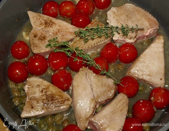 На чистой сковороде разогреваем оливковое масло. Зубчик чеснока разрезаем на 4 части. Обжариваем 2 минуты помидоры черри, каперсы, чеснок, анчоусы. Добавляем вино, доводим до кипения. Добавляем тунец и тимьян, тушим несколько минут под крышкой до необходимой для вас готовности рыбы. Снимаем с огня и даем отдохнуть 1–2 минуты. Выкладываем на тарелку и подаем.