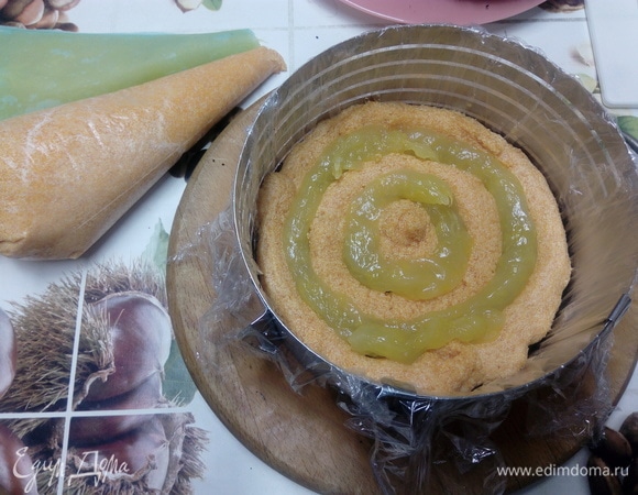 Ставим кондитерское кольцо на тарелку или поворотный столик, кладем в него первый корж. При помощи мешка выкладываем крем ровным слоем на корж. Внутрь кремовых колец выкладываем апельсиновый курд (примерно половину всего количества). Поверх крема и курда кладем второй корж и опять выкладываем крем и курд. Накрываем третьим коржом и ставим в холодильник на 30 минут, чтобы коржи схватились с кремом.