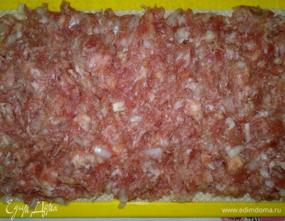 На доску положить вафельный корж, на него выложить слой фарша толщиной примерно 1 см.