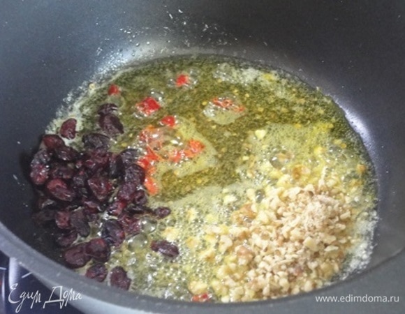 В казане или сотейнике с толстыми стенками раскалить масло, бросить туда специи №1 и клюкву (можно изюм или курагу) с орехами. Все перемешать и обжаривать на умеренном огне 3–5 минут.