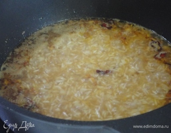 Добавить рис и специи №2. Залить горячей водой так, чтобы она покрывала рис на 2–3 см. Довести до кипения и держать на сильном огне, пока уровень воды не сравняется с уровнем риса. Затем прикрыть крышкой и томить на слабом огне до готовности.