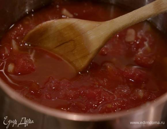 Приготовить томатный соус: четыре зубчика чеснока почистить, мелко порубить и обжарить в тяжелой кастрюле на оливковом масле, затем добавить консервированные помидоры, посолить и, помешивая, уварить, так чтобы соус загустел.