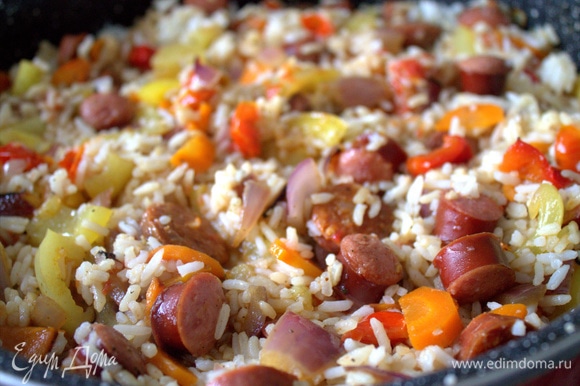 Распределяем рис по всей сковороде, добавляем 1–2 стакана воды и оставляем рагу тушиться под крышкой.