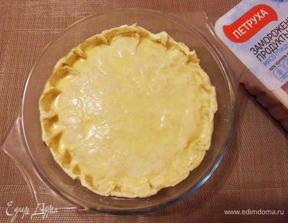 Слоеное тесто разморозить. Раскатать или немного растянуть. Накрыть начинку тестом. Оформить бортик (по желанию). Смешать молоко и желток, смазать тесто кулинарной кисточкой. Наколоть тесто вилкой в нескольких местах. Поставить в середину предварительно разогретой до 200°C духовки на 20–25 минут.