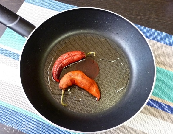 В сковороду положить перец чили, жарить 1–2 минуты. Перчики должны зажарится и отдать свой аромат маслу. Осторожнее! Перцы надуваются и могут взорваться!