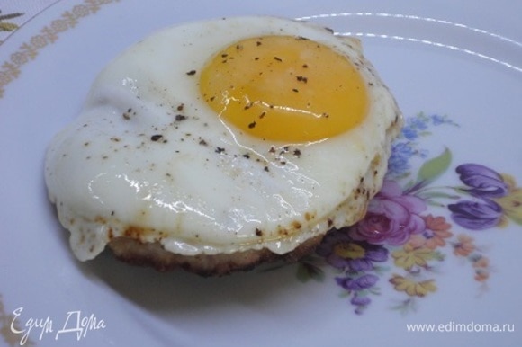 Шницель выкладываем на тарелку, сверху кладем поджаренное яйцо со свежемолотым перцем.