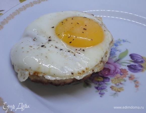 Шницель выкладываем на тарелку, сверху кладем поджаренное яйцо со свежемолотым перцем.