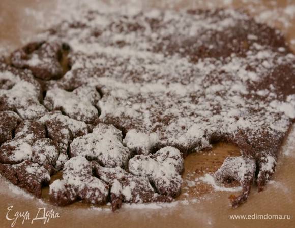 Охлажденное тесто раскатать между двумя листами бумаги для выпечки в пласт толщиной полсантиметра, посыпать сверху мукой и формочкой вырезать печенье.