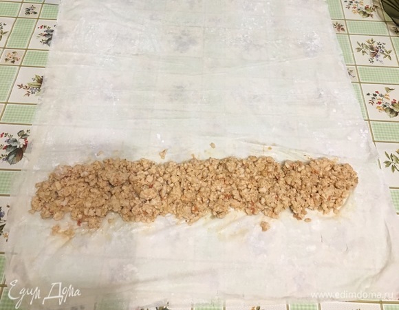 Взять два листа тесто фило и положить один на другой. Выложить по краю теста начинку.