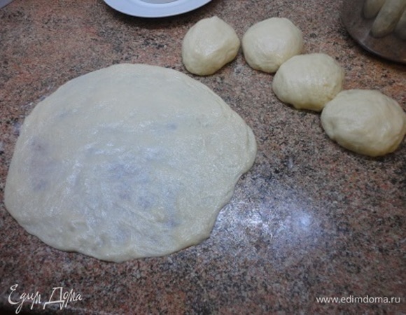 Кусочек мягкого сливочного масла размазываем на столе и равномерно растягиваем кусочек теста руками. Сверху смазываем сливочным маслом. Всего может потребоваться и меньше масла.