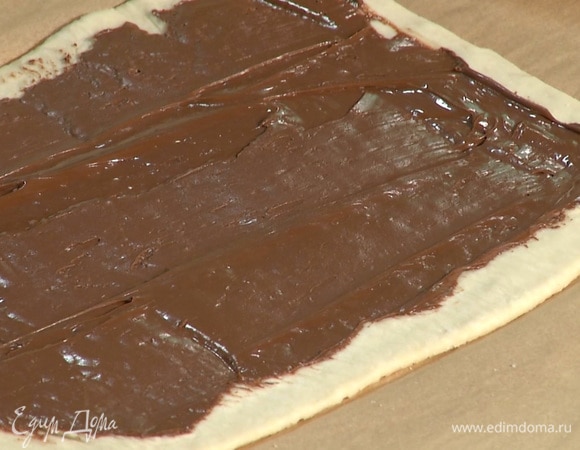 На тесто равномерно нанести шоколадную пасту, немного отступая от краев.  