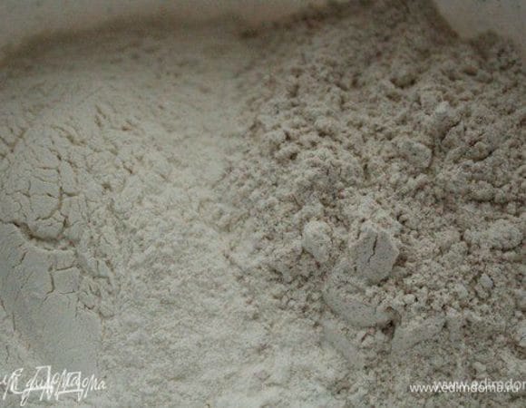 Замочить чернослив в роме минимум на час. Соединить 2 вида муки, втереть в них дрожжи, затем добавить соль и воду и замесить тесто. Я это делаю при помощи миксера насадками для замешивания теста. Сначала 2 минуты на низкой скорости, потом скорость увеличить и месить еще 7 минут, пока тесто не станет гладким и эластичным.