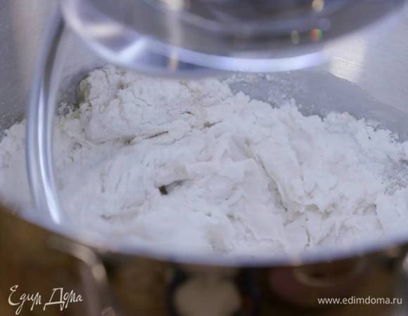 Просеять 150 г муки через сито в чашу кухонного комбайна, добавить дрожжи, сахар, щепотку соли, влить 65 мл теплой воды и вымешать все на низкой скорости насадкой-крюком.