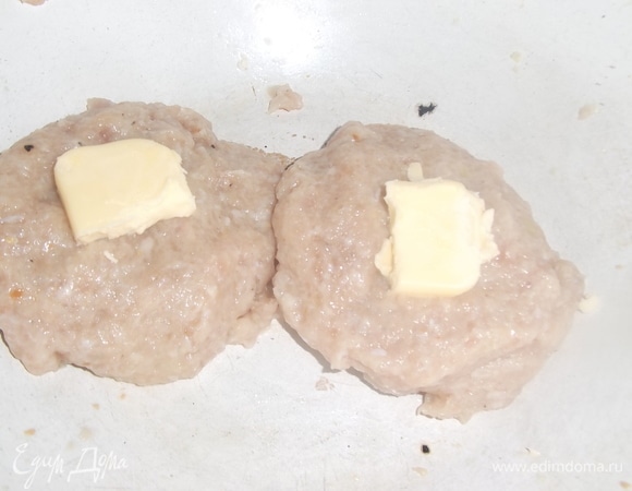 Влажными руками сформировать из фарша лепешку, на середину которой выложить 5 г сливочного масла. Каждую лепешку сформировать в котлету. Масло должно быть внутри.