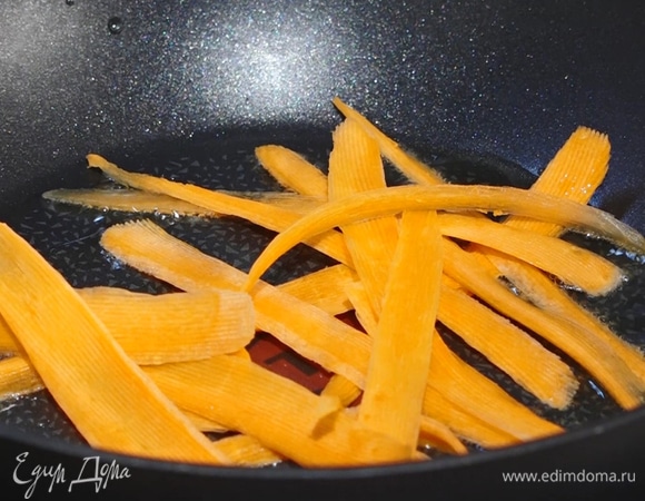 В сковороду-вок налить масло, добавить морковь, обжарить несколько минут.  