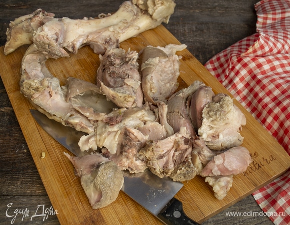 Достаем вареную рульку из бульона, аккуратно снимаем кожу, срезаем с нее жир. Мясо отделяем от костей.