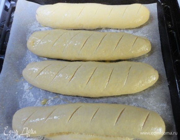 Разогреть духовку до 180°C. Подошедшие багеты смазать смесью яйца и молока и сделать надрезы.