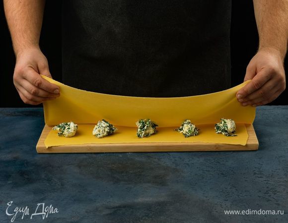 Тесто раскатайте в тонкий пласт. На одной половине теста выложите начинку на определенном расстоянии друг от другу.