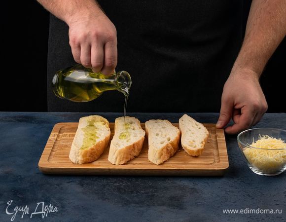 Сыр натрите на крупной терке. Хлеб нарежьте на ломтики, полейте оливковым маслом.