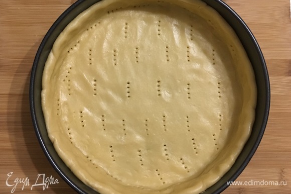 Раскатать тесто и выложить по форме размером 24 см, вылепливая бортик. Наколоть дно вилкой и выпекать в течение 15 минут при 180°C.