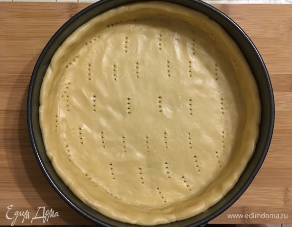 Раскатать тесто и выложить по форме размером 24 см, вылепливая бортик. Наколоть дно вилкой и выпекать в течение 15 минут при 180°C.