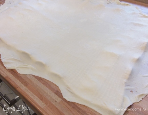 На припыленной мукой поверхности тонко раскатать тесто прямоугольной формы. Полотенце присыпать мукой и аккуратно перенести тесто на полотенце. При переносе тесто нужно осторожно и равномерно растягивать руками.