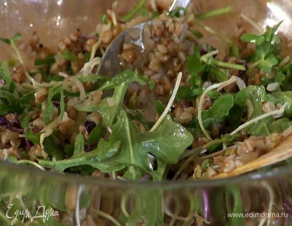 Отваренную гречку, обжаренный лук с чесноком, проростки и руколу выложить в салатницу, полить заправкой и перемешать.