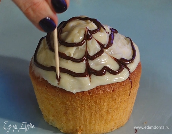 Ганаш из темного шоколада налить сверху тонкими кругами, затем зубочисткой соединить полосы, таким образом сделать рисунок в виде паутины.